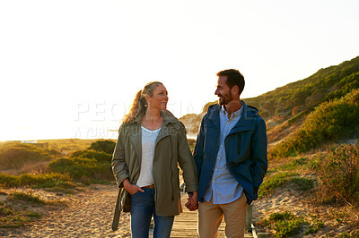 Buy stock photo Cropped shot of an affectionate couple walking hand-in-hand outdoors