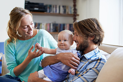 Buy stock photo Shot of a young couple playing with their baby at home