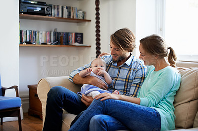 Buy stock photo Shot of a young couple playing with their baby at home