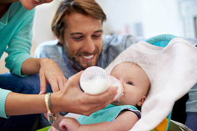Buy stock photo Shot of a young couple feeding their baby at home