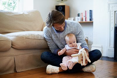 Buy stock photo Shot of a father sitting on the living room floor playing with his baby girl