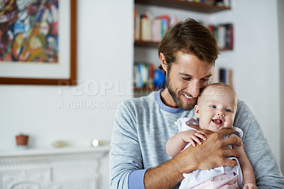 Buy stock photo Shot of a smiling father playing with his baby girl at home