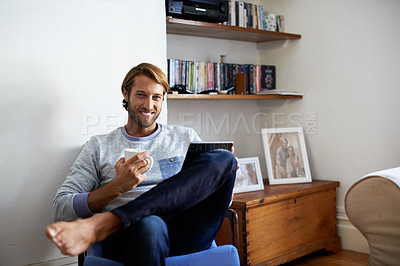 Buy stock photo Portrait of a young man using a digital tablet while relaxing at home