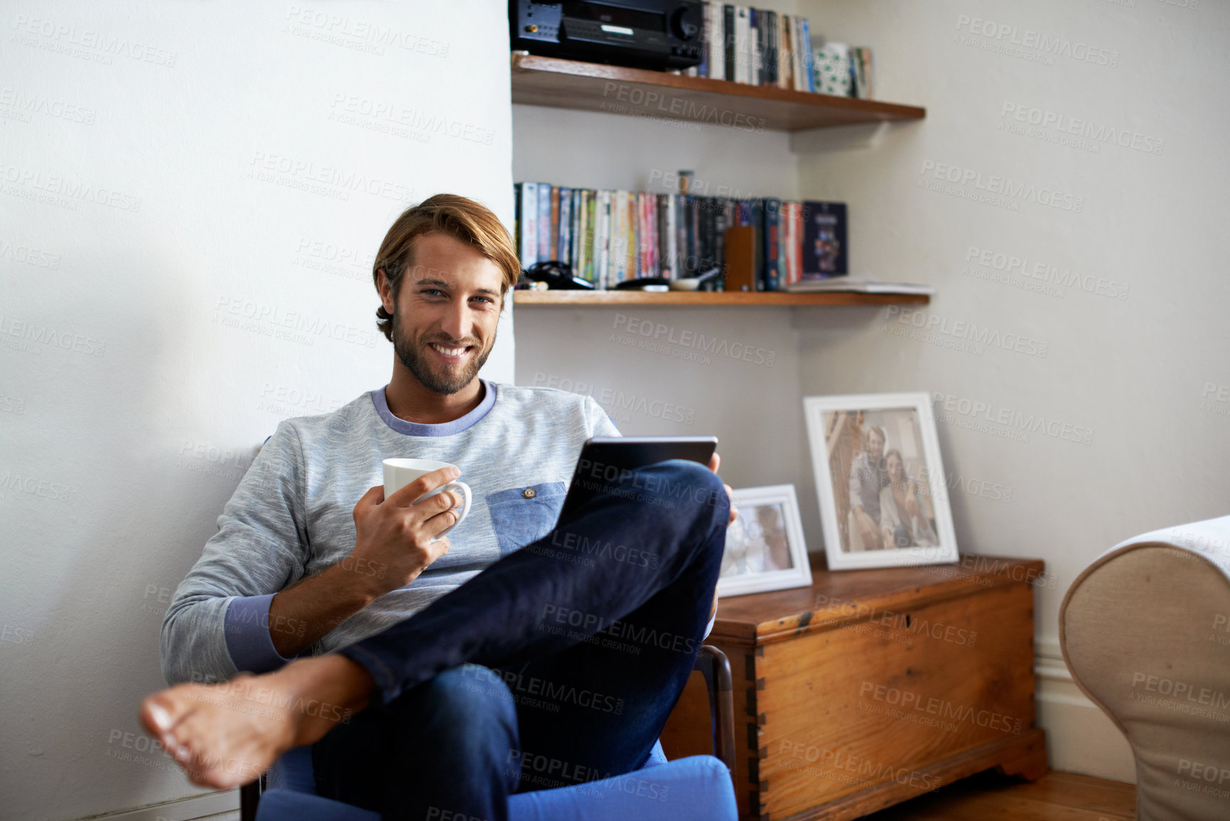 Buy stock photo Portrait of a young man using a digital tablet while relaxing at home