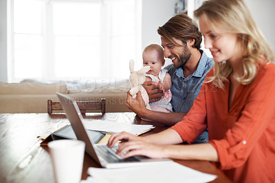 Buy stock photo Shot of a couple using a laptop while cradling their baby