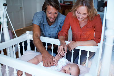 Buy stock photo Shot of a couple looking at their baby lying in a crib