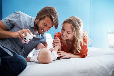 Buy stock photo Shot of a young couple playing with their baby on a bed