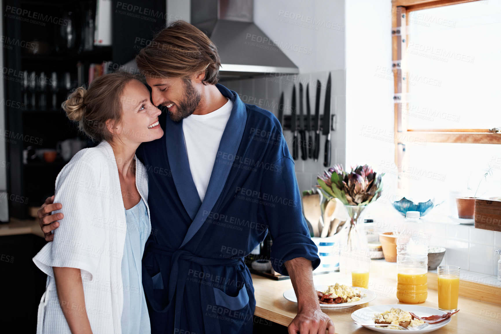 Buy stock photo Shot of a young couple sharing a moment together while cooking breakfast