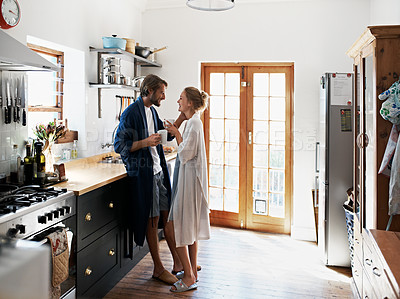 Buy stock photo Shot of a young couple drinking coffee in the kitchen in the morning