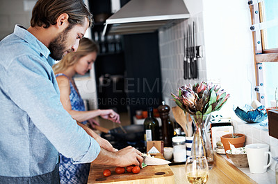 Buy stock photo Shot of a young couple cooking together in the kitchen