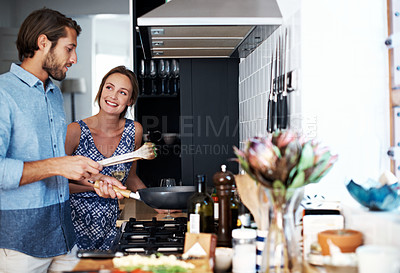 Buy stock photo Shot of a young couple cooking together in the kitchen