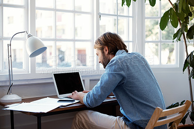 Buy stock photo Shot of a young man working on a laptop at home