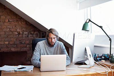 Buy stock photo Shot of a young man working on a laptop in his study at home