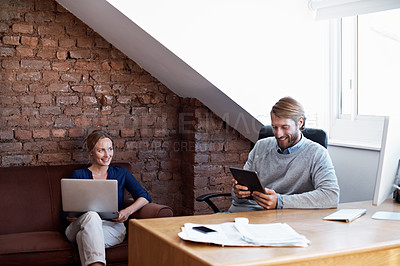 Buy stock photo Shot of a young couple using a digital tablet and laptop while relaxing at home