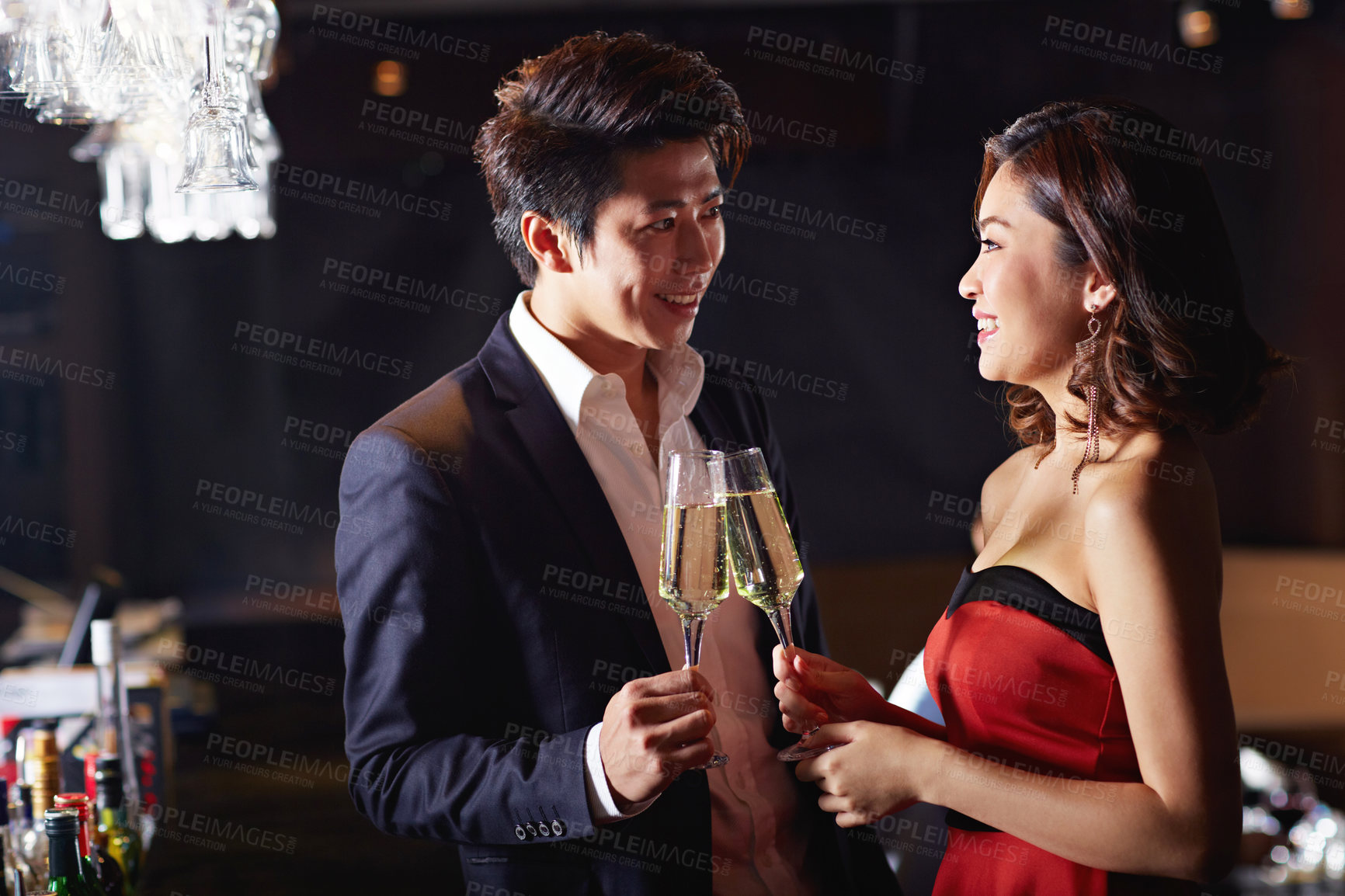 Buy stock photo Shot of a young asian couple toasting with champagne in a bar