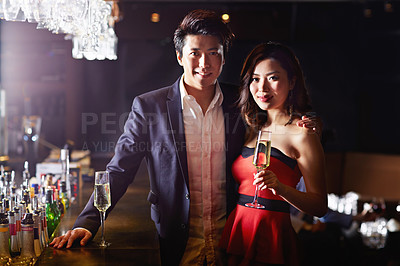Buy stock photo Portrait of a young asian couple drinking in a bar
