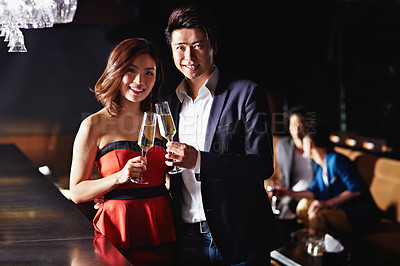 Buy stock photo Portrait of a young asian couple toasting with champagne in a bar