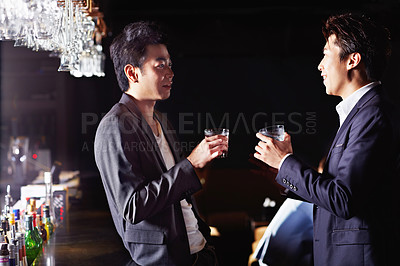 Buy stock photo Shot of a two male friends drinking and talking together in a nightclub