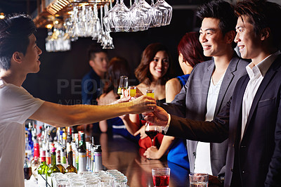 Buy stock photo Shot of two male friends drinking shots together in a club