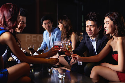 Buy stock photo Shot of a group of friends sitting in a nightclub enjoying drinks 