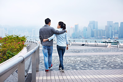 Buy stock photo Rearview shot of a young couple walking along the Hong Kong waterfront