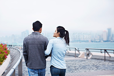 Buy stock photo Rearview shot of a young couple walking along the Hong Kong waterfront