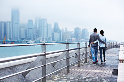 Buy stock photo Rearview shot of a young couple walking along the Hong Kong waterfront