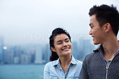 Buy stock photo Shot of a young asian couple walking along the Hong Kong waterfront