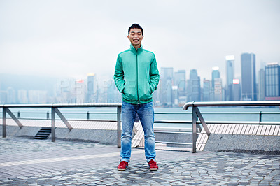 Buy stock photo Full length portrait of a handsome young asian man standing in ftont of the Hong Kong skyline