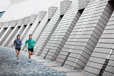 Buy stock photo Shot of a young man and woman jogging