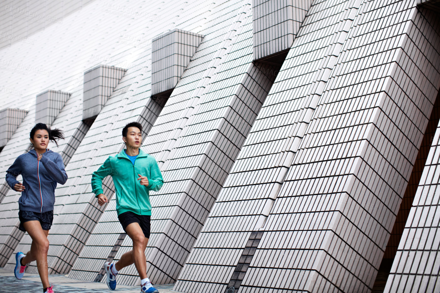 Buy stock photo Shot of a young man and woman jogging