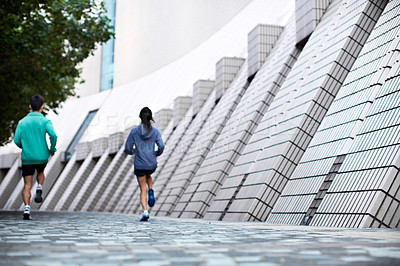 Buy stock photo Rearview shot of a young man and woman jogging