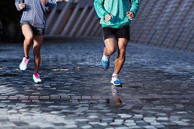 Buy stock photo Cropped shot of two unrecognizable people jogging along the pavement