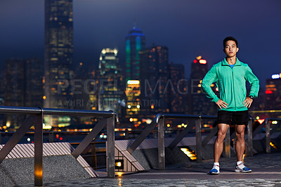 Buy stock photo Portrait of an athletic young man standing in front of the Hong Kong skyline at night