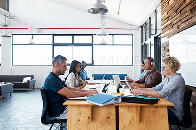 Buy stock photo Shot of a group of colleagues working on laptops around a table