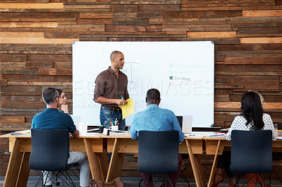 Buy stock photo Shot of a male office worker giving a financial presentation to his colleagues