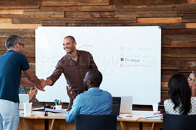 Buy stock photo Shot of two coworkers shaking hands during an office presentation