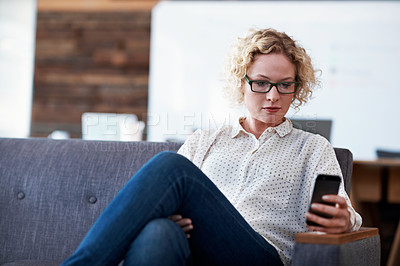 Buy stock photo Shot of a woman using her cellphone in a modern office