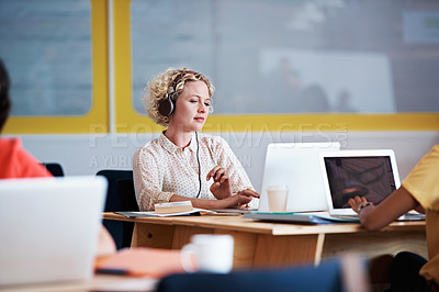 Buy stock photo Shot of a designer listening to music while working at her desk