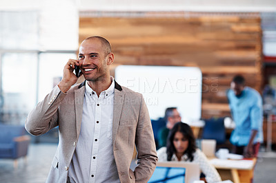 Buy stock photo Shot of a man talking on his cellphone with his colleagues blurred in the background