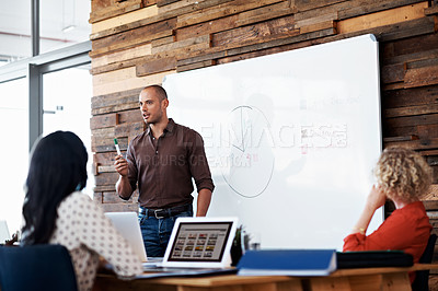 Buy stock photo Shot of a male office worker giving a financial presentation to his colleagues