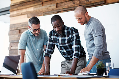 Buy stock photo Shot of a group of colleagues going through some paperwork