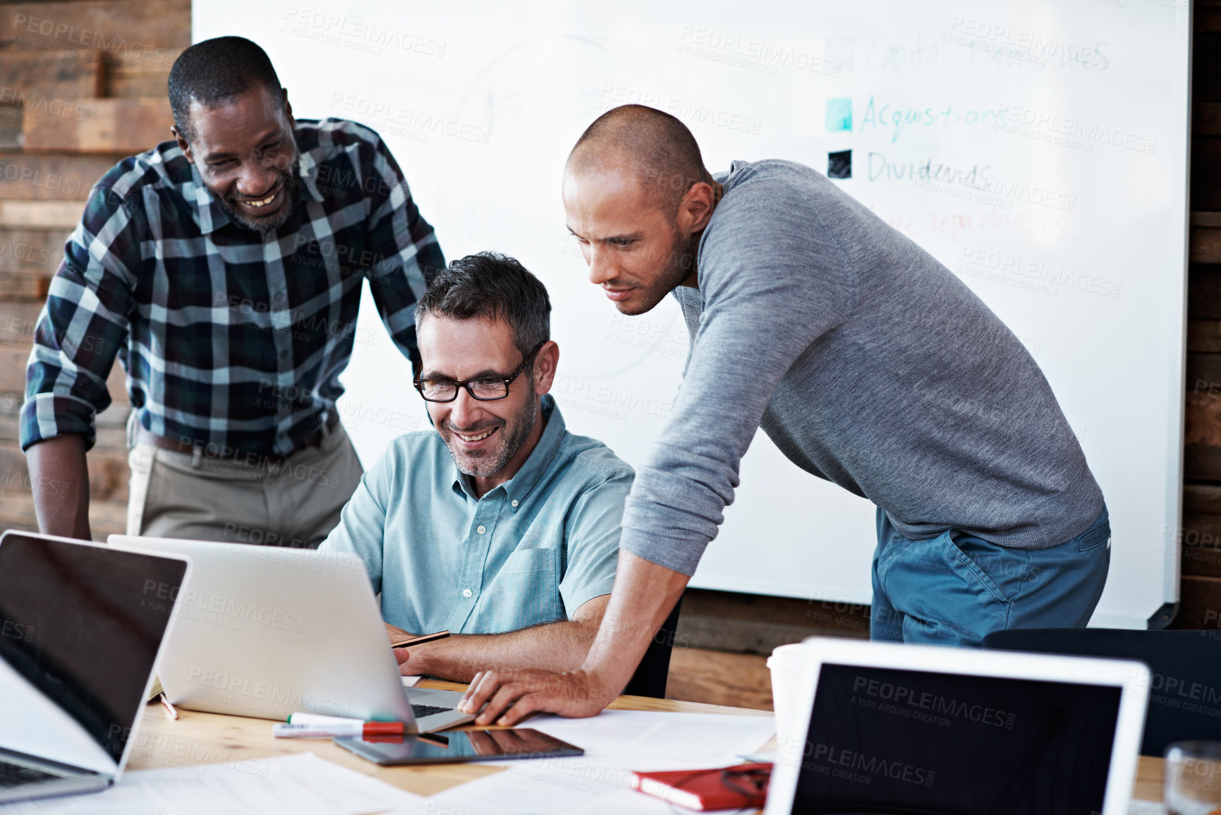 Buy stock photo Shot of a group of colleagues having a discussion while looking at a laptop