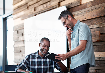 Buy stock photo Shot of a handsome man showing his colleague something on his digital tablet