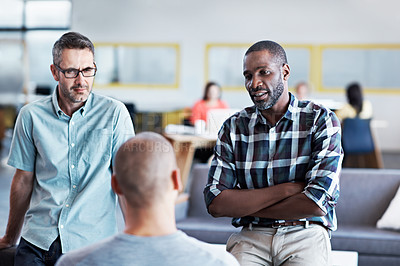 Buy stock photo Shot of a group of male colleagues having a conversation in an modern office