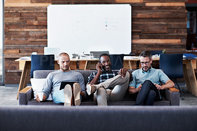 Buy stock photo Shot of a group of coworker using their gadgets at the office