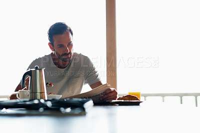 Buy stock photo Cropped shot of a handsome man eating breakfast while reading the paper