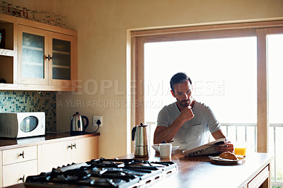 Buy stock photo Cropped shot of a handsome man eating breakfast while reading the paper
