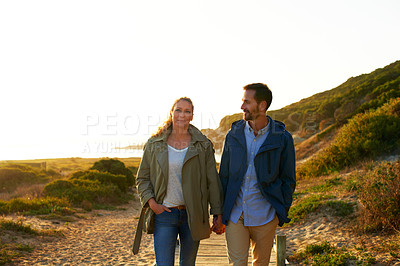 Buy stock photo Cropped shot of an affectionate couple walking hand-in-hand outdoors