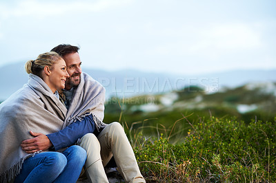 Buy stock photo Cropped shot of an affectionate couple wrapped in a blanket while sitting outdoors